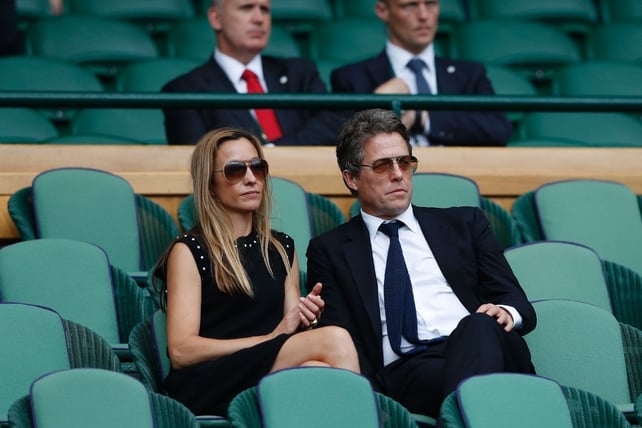 Hugh Grant and Anna Eberstein sit in the Royal box on Centre Court following the men's singles final match.