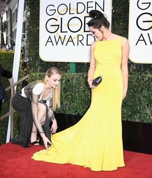 Sophie, while wearing Louis Vuitton, helped Maisie fluff out her yellow Ong-Oaj Pairam gown at the 74th Annual Golden Globes.