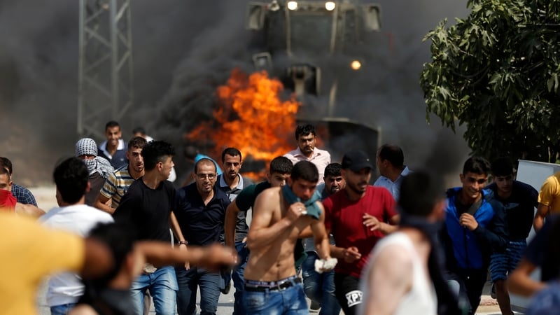 Palestinian youths run from the path of an Israeli army bulldozer during clashes in the village of Kobar