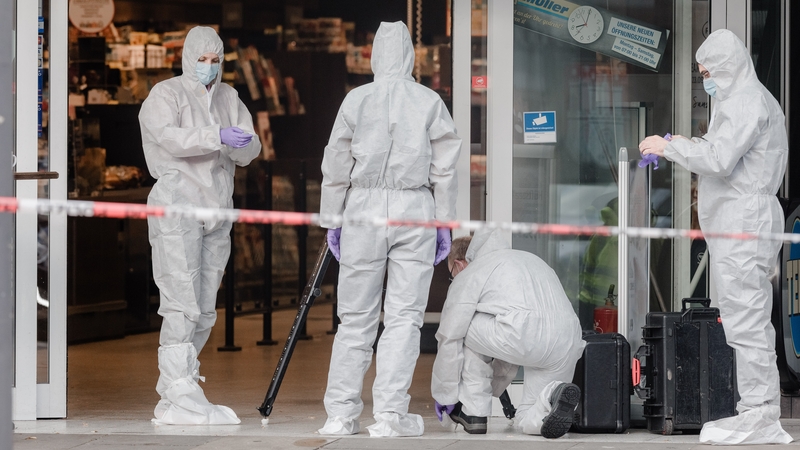 Police investigators work at the area around the supermarket in the northern German city of Hamburg