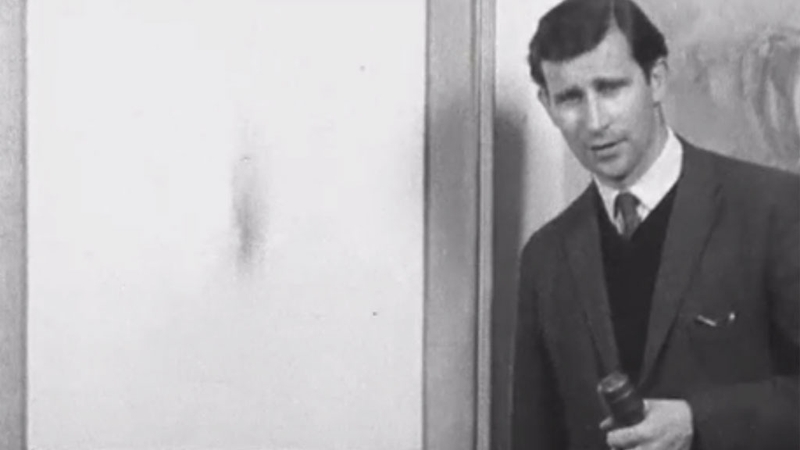 Brian O'Doherty standing beside a Louis le Brocquy painting in 1962