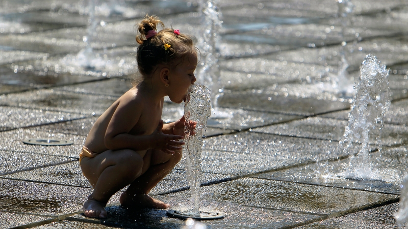 A child plays in a public fountain in Bucharest, Romania, today where temperatures were expected to reach 42C