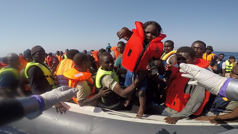 A small child is handed over to navy personnel during the rescue