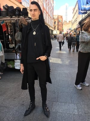 Alan Fournier's coat is from Zara, his polo is from Marks in Canada and trousers from H&M. He bought his shoes from a German Etsy store and his jewelry is from various shops and people he visited on his travels.
