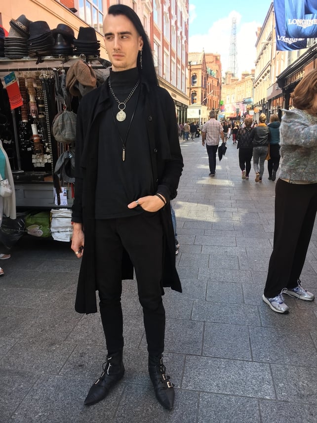 Alan Fournier's coat is from Zara, his polo is from Marks in Canada and trousers from H&M. He bought his shoes from a German Etsy store and his jewelry is from various shops and people he visited on his travels.