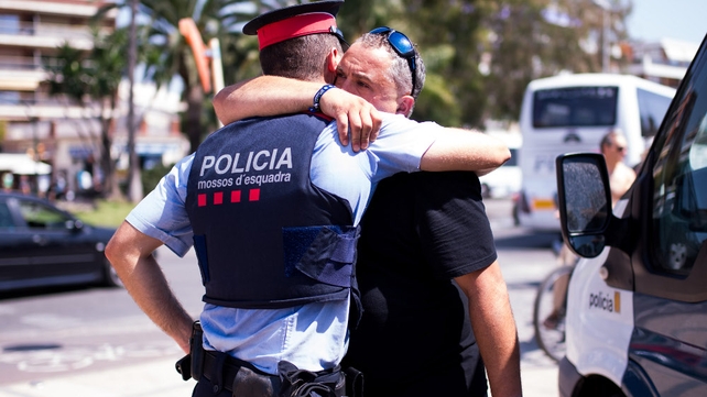 A man embraces a police officer near the area where five attackers were shot dead in Cambrils