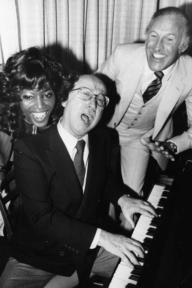 Musician Sammy Cahn playing the piano, with singer Lucienne Camille and Bruce Forsyth on December 5, 1980