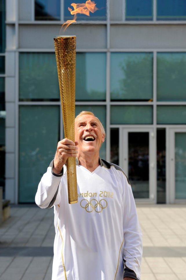 Bruce Forsyth carrying the Olympic Flame on the Torch Relay leg through Kensington and Chelsea in 2012