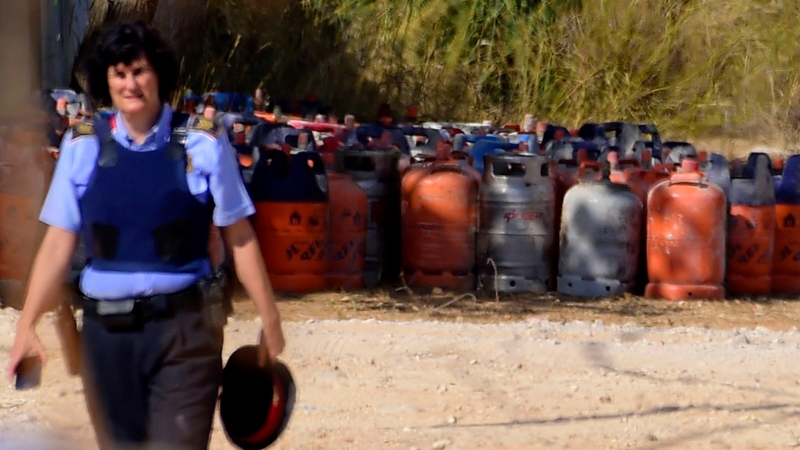 A policewoman walks past dozen of gas canisters in Alcanar