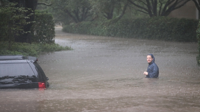 A man is seen in a flooded street of River Oaks in Houston