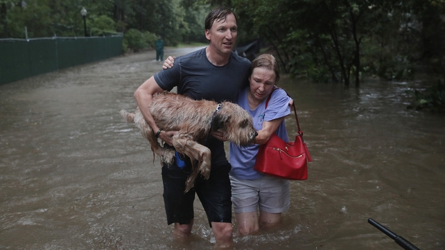 Andrew White (L) helps a neighbour after rescuing her and her dog in Houston