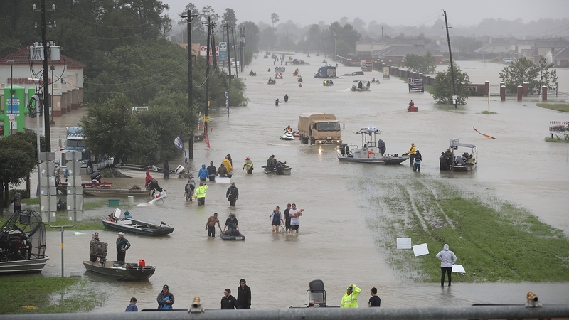 People walk down a flooded street as they evacuate their homes