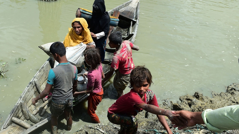 Local Bangladeshis help Rohingya Muslim refugees to disembark from a boat on the Bangladeshi side of Naf river
