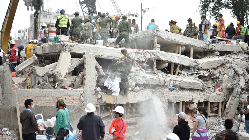 Rescuers and volunteers clearing rubble and debris at the site where a multistory building was flattened