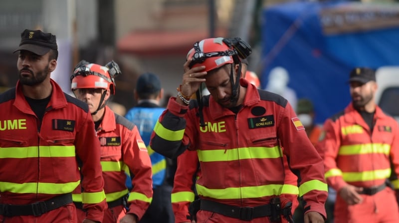 Rescuers leave a flattened multistory building after searching for survivors at the Roma neighbourhood in Mexico City