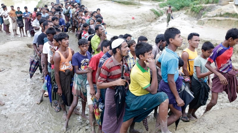 Rohingya refugees stand in a queue as they wait to collect relief goods yesterday in Coxsbazar, Bangladesh