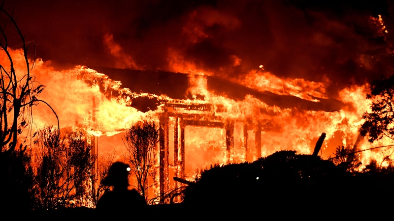 Firefighters assess the scene as a house burns in the Napa wine region of California