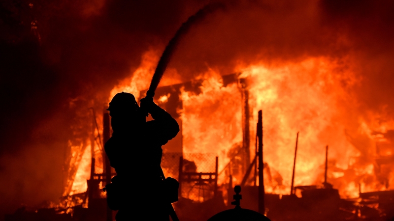 A firefighter douses flames as a home burns in the Napa wine region of California