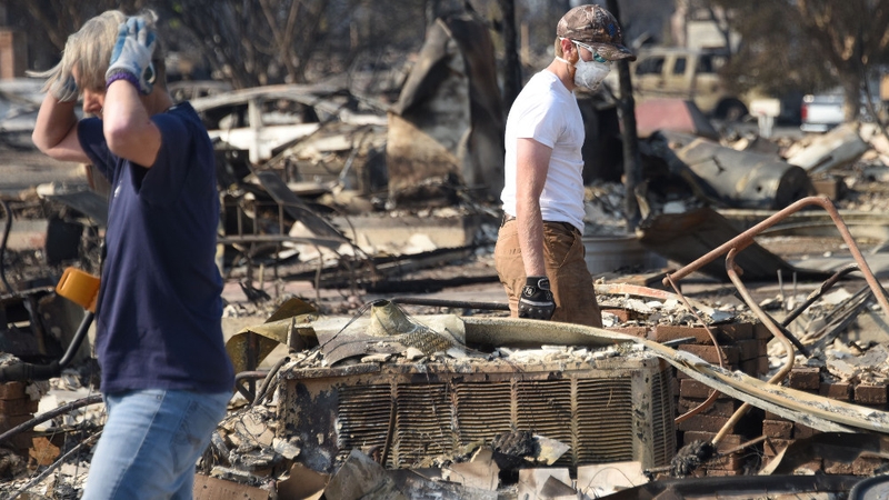 Ben Pederson (R) looks for salvageable items in the remains of his family's home was destroyed by wildfire in Santa Rosa
