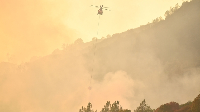 A helicopter attempts to extinguish flames in Calistoga by dropping water