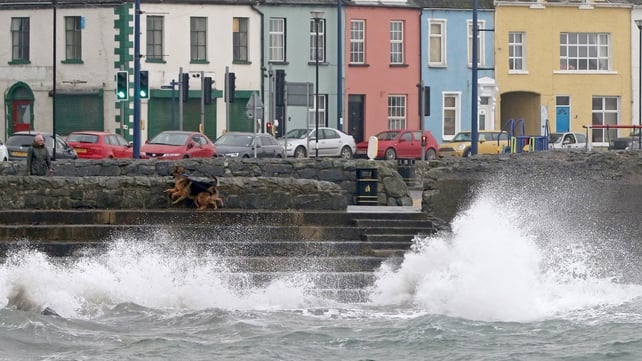 A woman walks her dogs beside the stormy sea in the coastal village of Donaghadee, Co Down