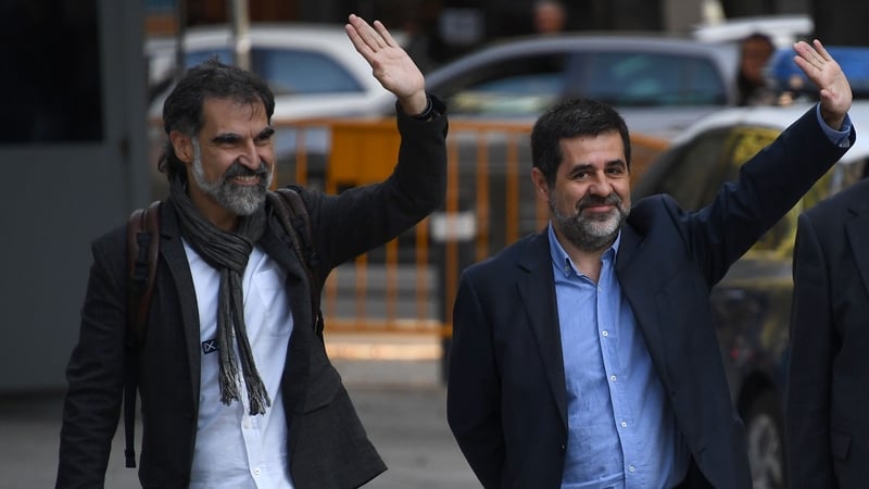 Jordi Sanchez and Jordi Cuixart wave to supporters as they arrive at the court in Madrid