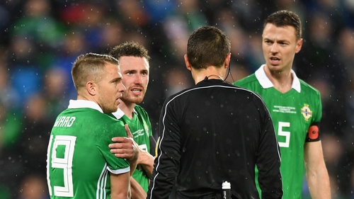 Northern Ireland players surround the referee after a penalty is awarded.