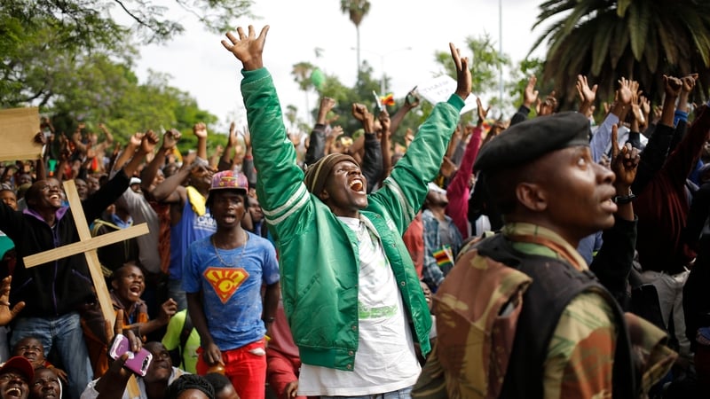 People react to a military helicopter overhead as they make their way towards Robert Mugabe's residence