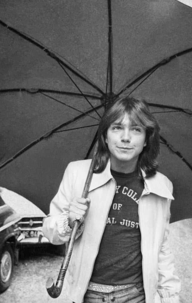 David Cassidy walking down a road in London with an umbrella in 1974