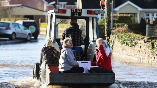A tractor helps women through the floods in Mountmellick, Co Laois