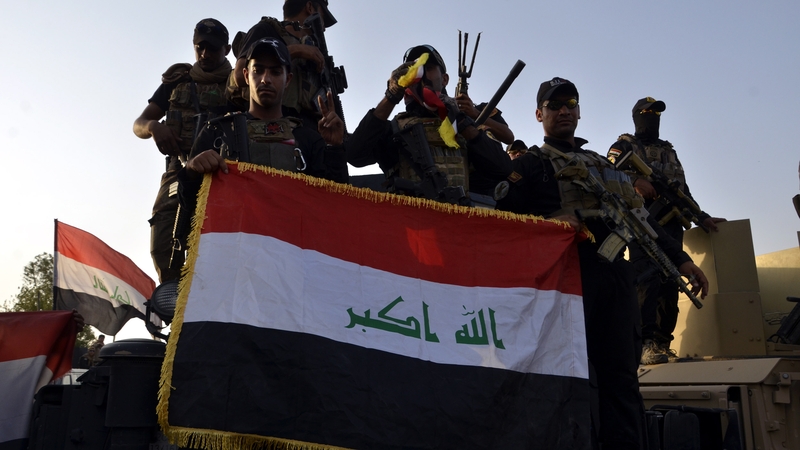 Iraqi soldiers display a flag in central Mosul