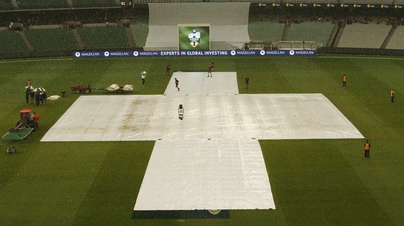 Covers are put on over the pitch as rain falls