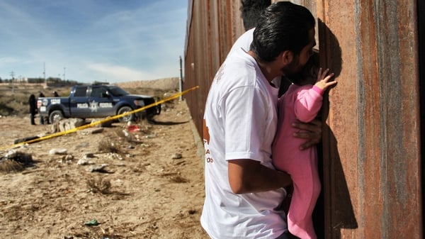 A man holds a baby next the border wall between Mexico and United States at Ciudad Juarez