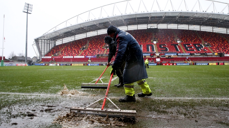 Ground staff remove excess water from the pitch at Thomond Park