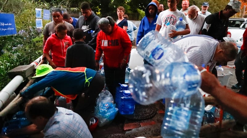 Residents queue for water at a natural spring