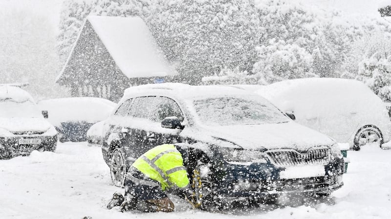 A man fits snow chains to his car in the village of Brenchley in southeast England