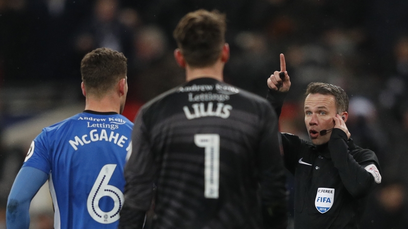 Referee Paul Tierney (r) listens to VAR decision to disallow Erik Lamela's goal