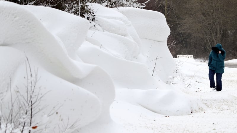 A woman walks past snow accumulations near Athy in Co Kildare after an overnight snowfall