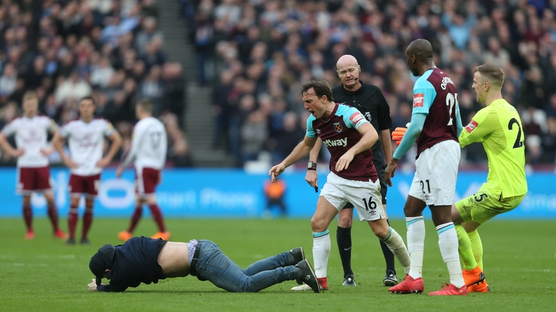 West Ham United's Mark Noble wrestles with a pitch invader at the London Stadium