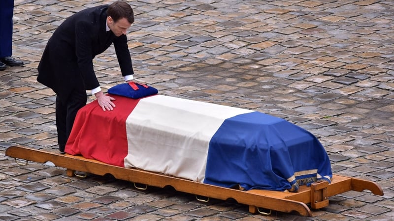French President Emmanuel Macron in front of the flag-draped coffin of Lieutenant-Colonel Arnaud Beltrame
