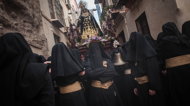 Penitents of 'Santa Cruz' brotherhood rest as they take part in a procession in Malaga