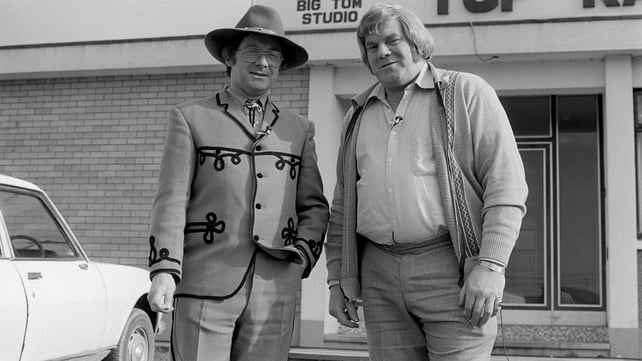 Broadcaster Donncha Ó Dúlaing (left) with Irish country music singer Big Tom, outside the latter's recording studio in the town of Castleblayney, County Monaghan, during the filming of RTÉ Television's 'Donncha's Travelling Roadshow' in March 1980.