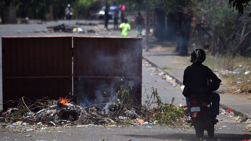 A biker rides past a barricade during protests against the government's reforms in Managua
