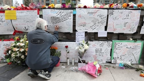 A man leaves a notes at a makeshift memorial for the victims in Toronto