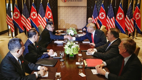 US President Donald Trump and North Korea's leader Kim Jong Un shake hands as they sit down with their delegations for the US-North Korea summit at the Capella Hotel in Singapore
