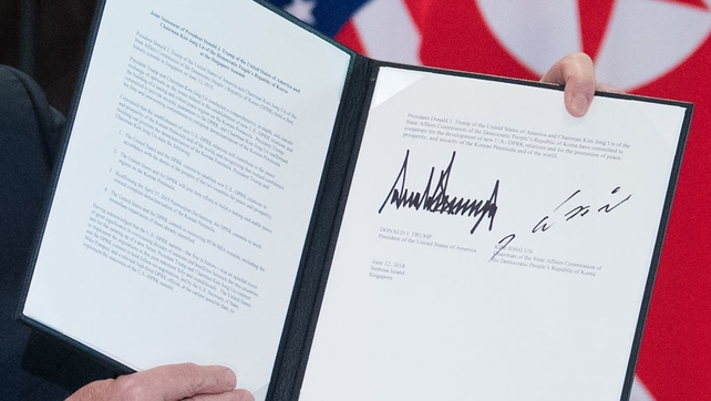 Donald Trump holds up a document signed by him and Kim Jong-un following a signing ceremony during their summit