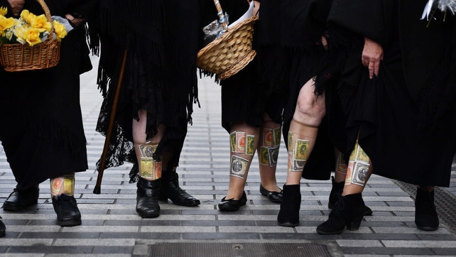 Women dressed as 'Shawlies' look on as Prince Charles and his wife visit the English Market in Cork