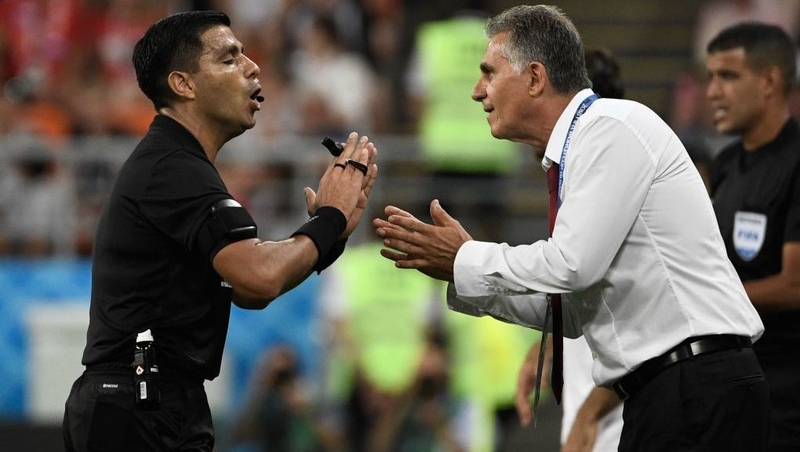 Referee Enrique Caceres has words with Iran's Portuguese coach Carlos Queiroz