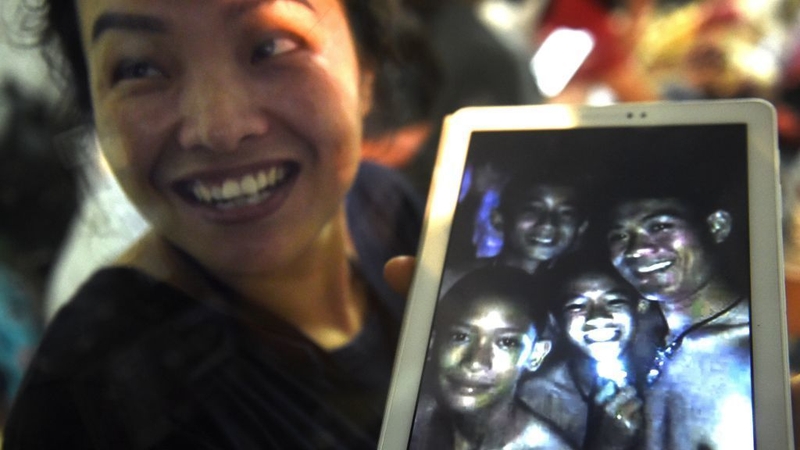 A family member shows a picture of four of the 12 trapped boys