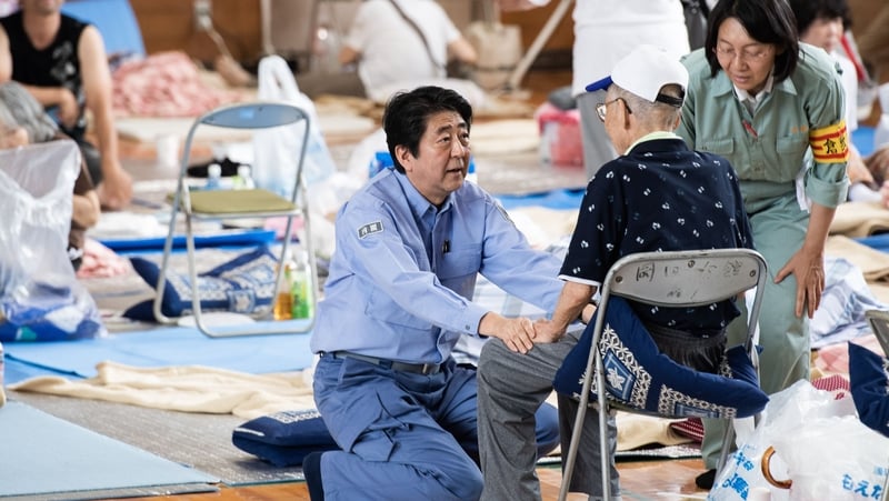 Shinzo Abe (C) visits a shelter for people affected by the recent flooding in Mabi, Okayama prefecture